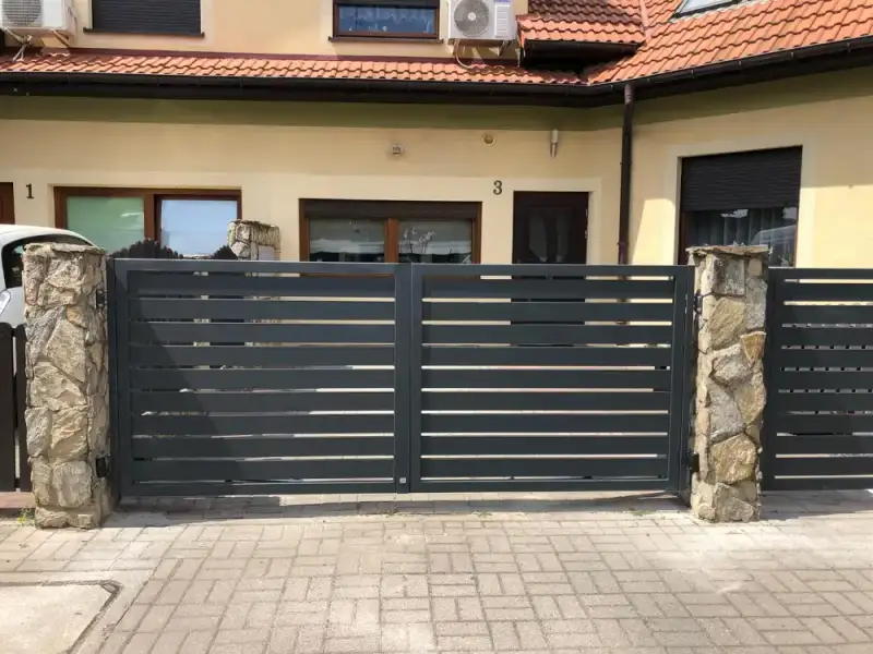 Front domu z bramą, furtką i słupkami z kamienia