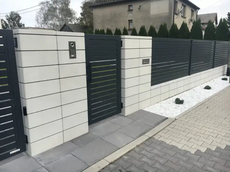 Nowoczesne ogrodzenie z dużych jasnych bloczków i wypełnienia z profili stalowych