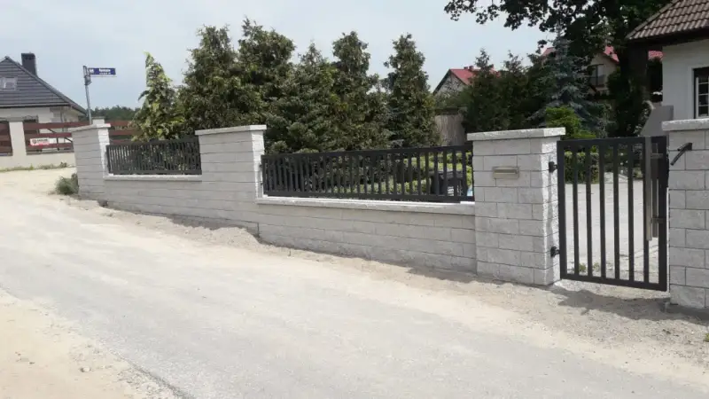 Długi odcinek ogrodzenia wzdłuż drogi dojazdowej z furtką i bramą
