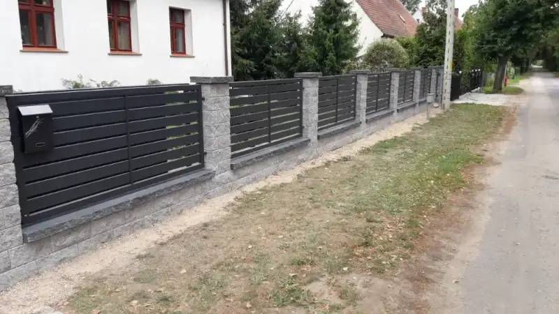 Ogrodzenie z bloczków i palisady przy drodze gminnej
