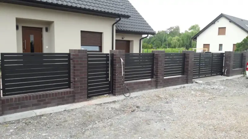 Ogrodzenie z poziomymi profilami i brązowymi słupkami przed domem