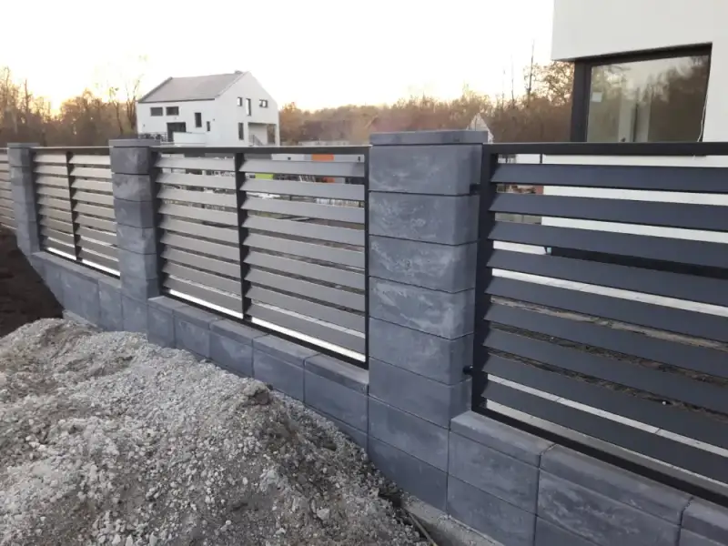 Palisada na ciemnych słupkach z bloczków ogrodzeniowych