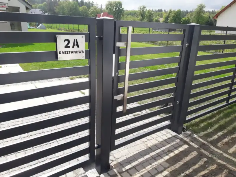 Detal poziomej palisady z numerem posesji na furtce